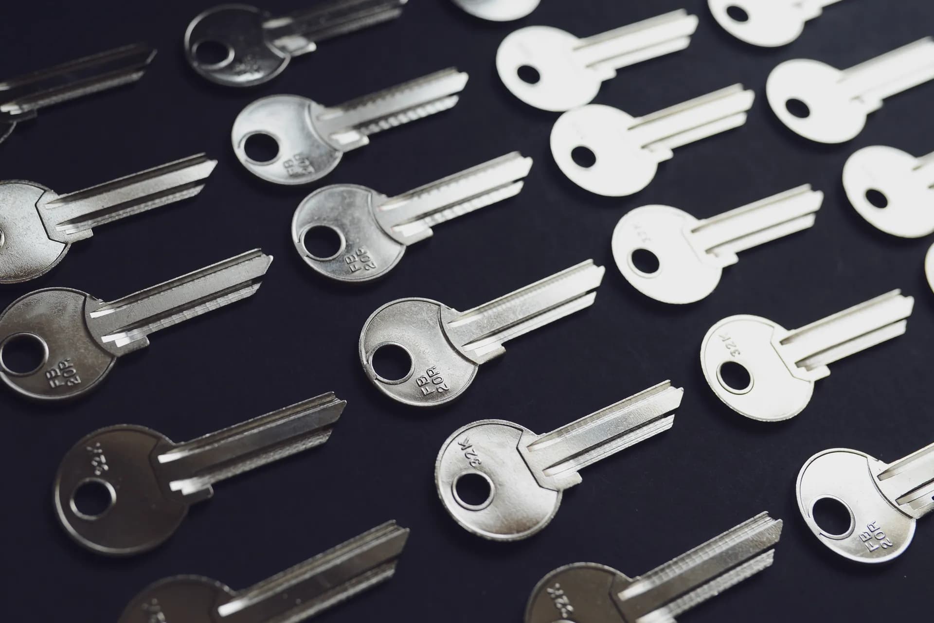 Rows of silver and white blank keys laid out diagonally on a dark surface